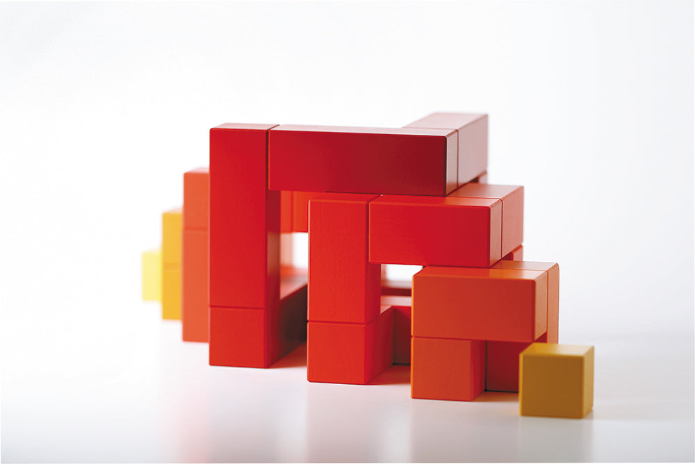 Red Naef Cubicus toy ungrouped and positioned to make a pyramid like shape on a white background.