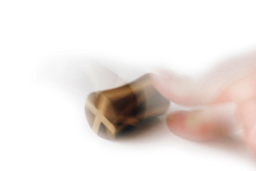 Blurred picture of a hand spinning the Naef tip spinning tops on a white background