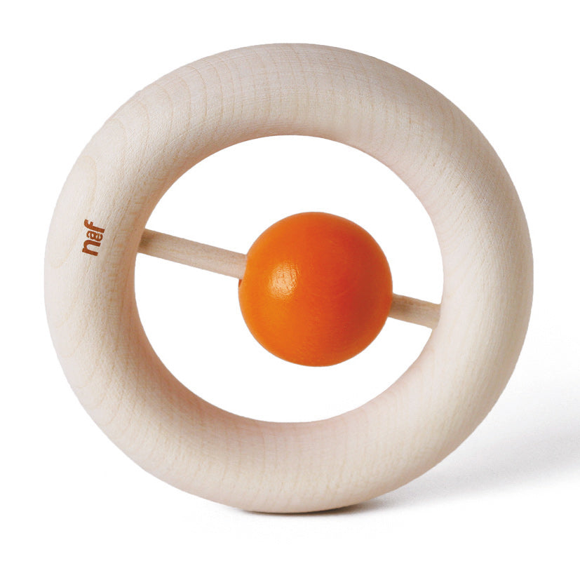 Naef's wooden Kauring baby teether stood up on end highlighting donut design with small orange rattle in the centre. Toy is placed on a white background.