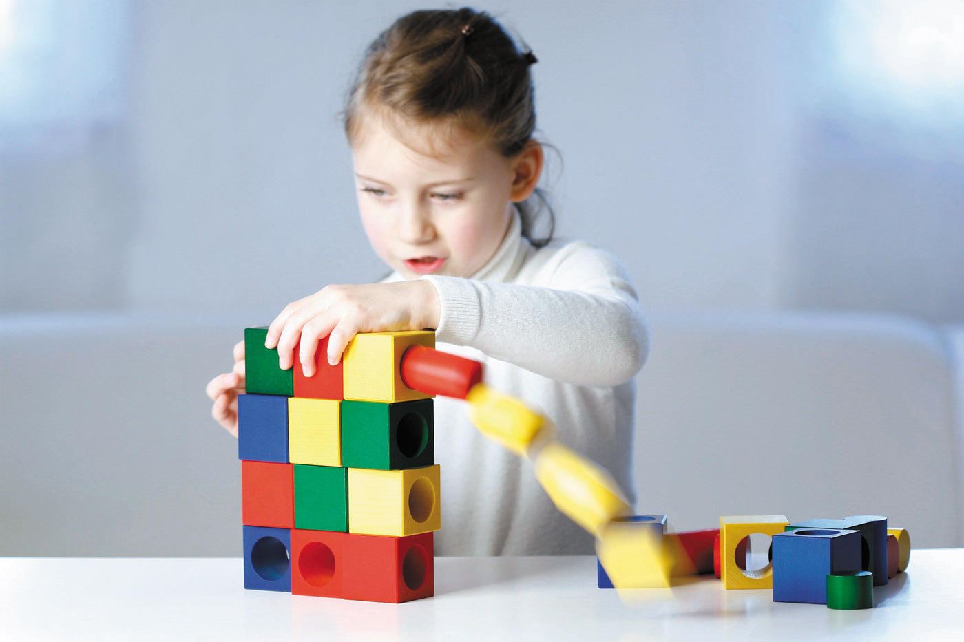 Pieces of the Naef Ligno wooden building blocks set stacked on a beige background