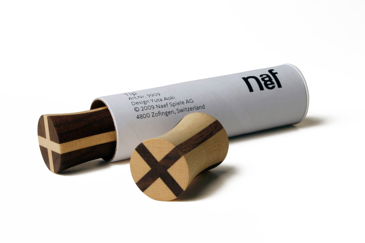 Naef premium wooden spinning top blocks next to their white tube packaging on a white background