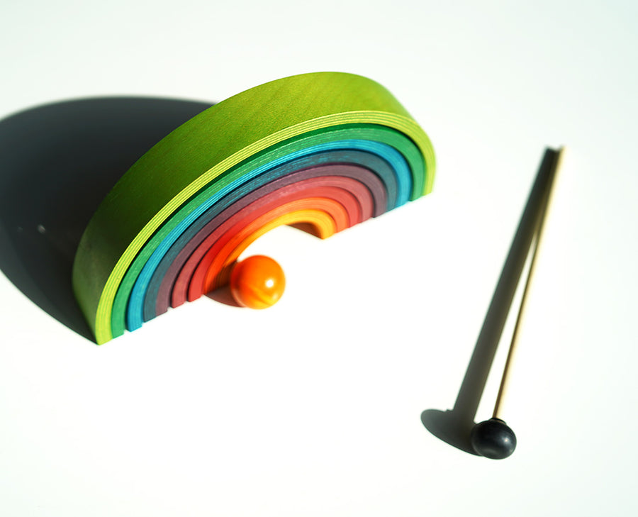 9 pieces of Naef's stacking wooden rainbow upturned on a white background.