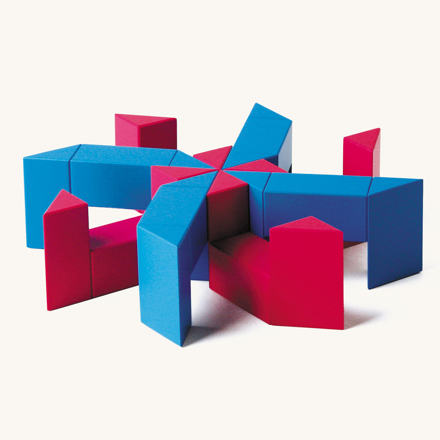 Red and blue Naef ponte toy blocks stacked in a geometric tower on a beige background