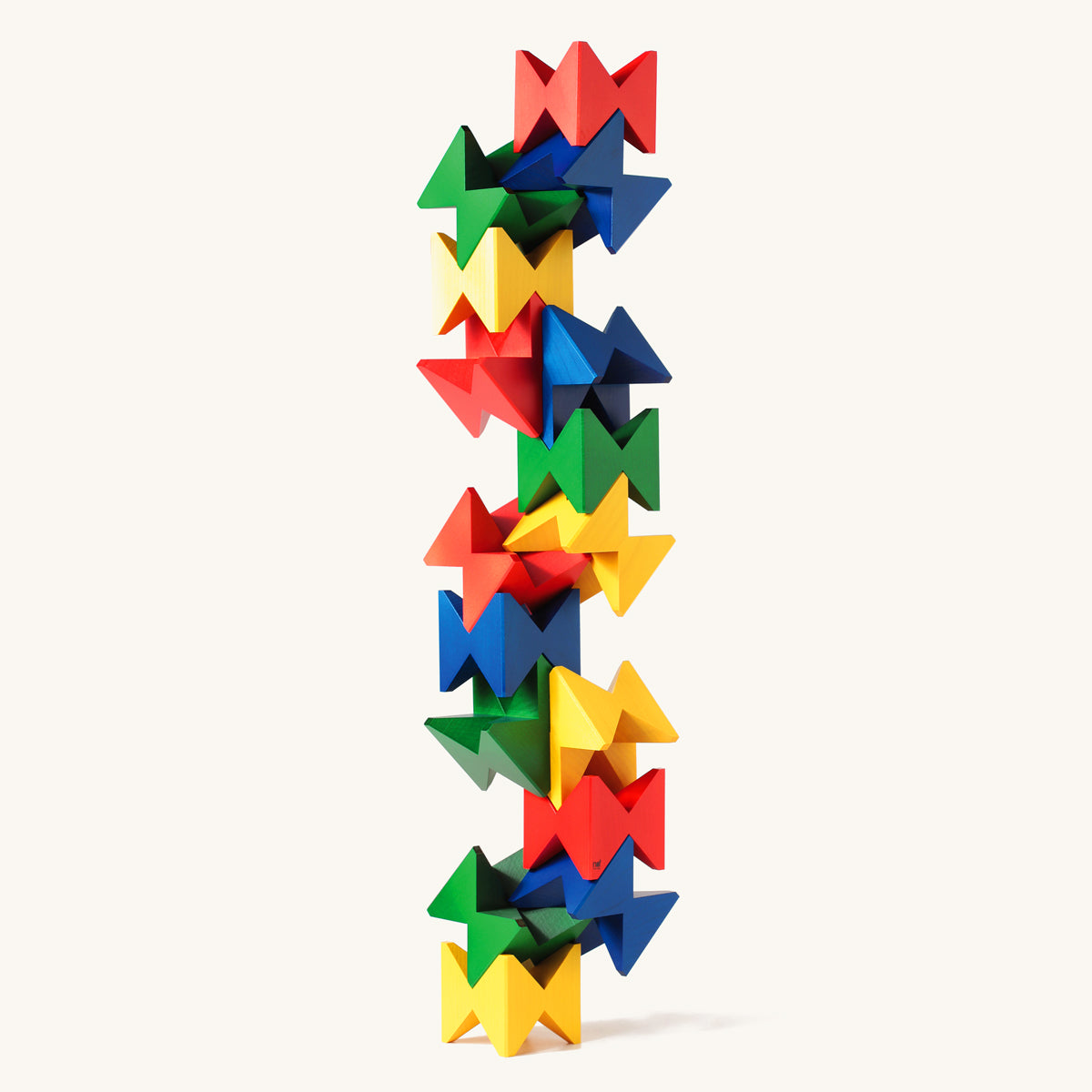 Naef plastic-free multicoloured geometric toy blocks stacked in a complex tower on a beige background