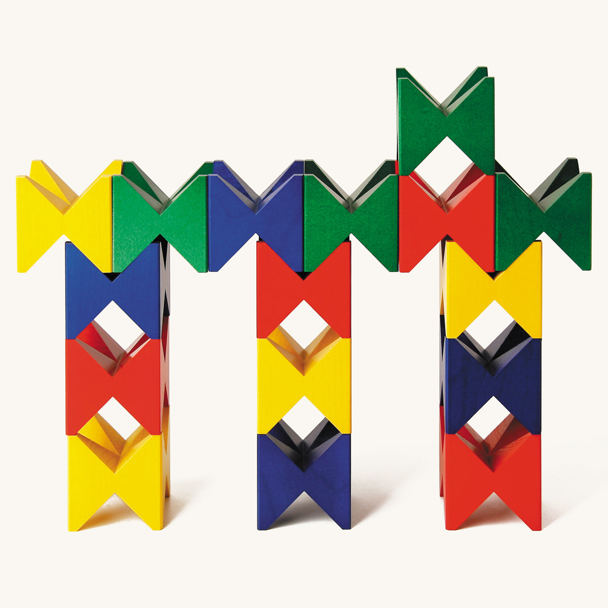 Naef precision manufactured wooden toy blocks in a geometric tower on a beige background