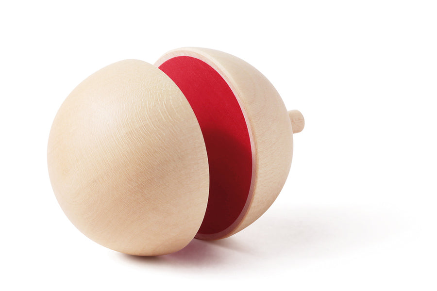 Naef spinning top on its side showing the red interior colouring on a white background