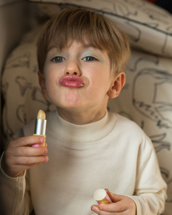 A child's wearing the Namaki child friendly lip balm on their lips holding the balm packaging in their hand 