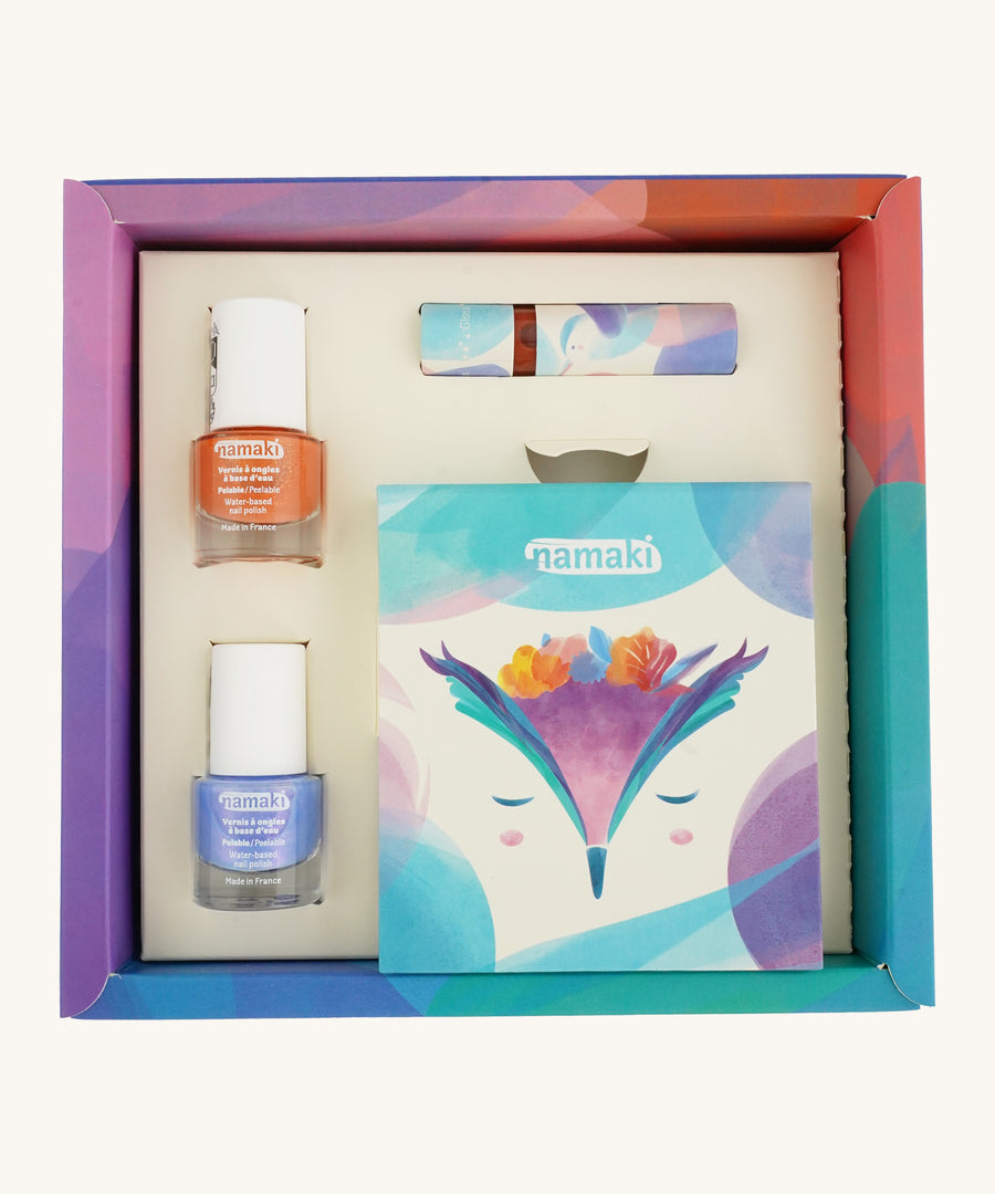 An open cardboard box for the Namaki fairy moonlight make up set which includes a blue and orange nail polish, a eye shadow set and a lipgloss on a cream background.