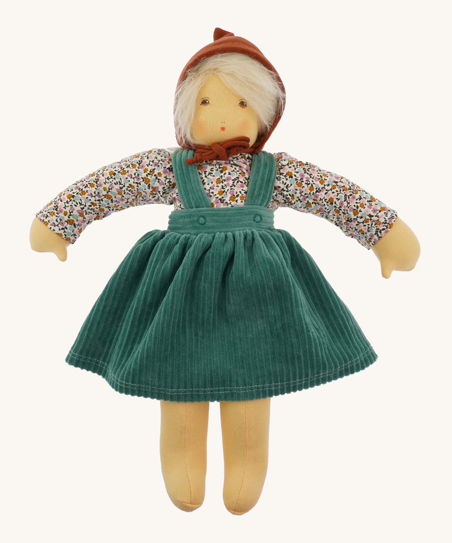 Nanchen Waldorf Doll - Lotte, an organic doll wearing a floral blouse, green cord pinafore dress and a brown bonnet. 