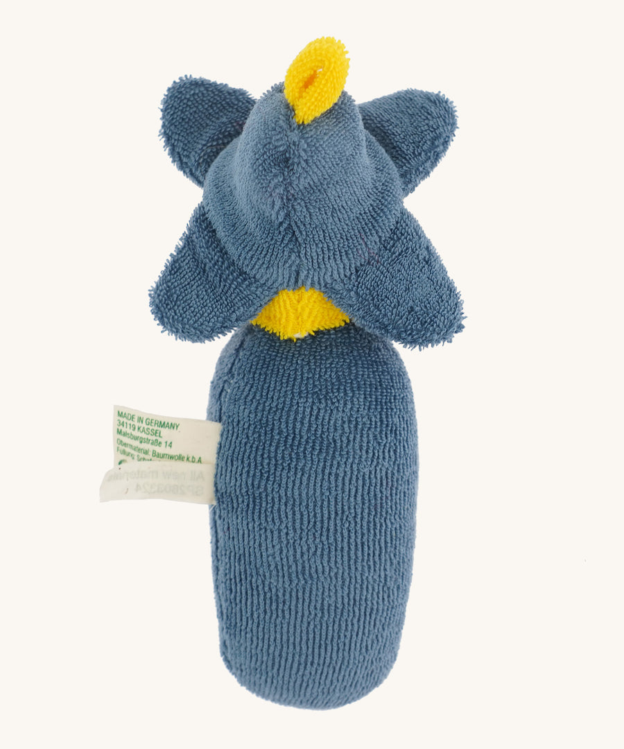 The back of the Nanchen Flower Rattle Doll - Forget-Me-Not, this is a soft, organic and handmade sensory doll toy with a blue body, a little blue hat with blue forget-me-not leaves and a yellow strip of fabric to mimic hair. This doll also has an adorable face with blue eyes