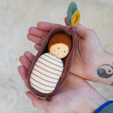 Nanchen Oak Baby Waldorf Doll - Stripes. A little organic grasping doll in a brown velvet cradle in a persons hands.