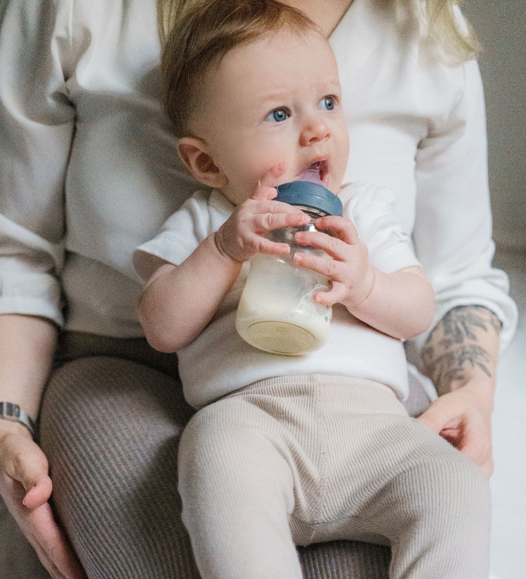 A baby drinking from the Lola & Lykke Natural Flow Baby Bottle with cap.