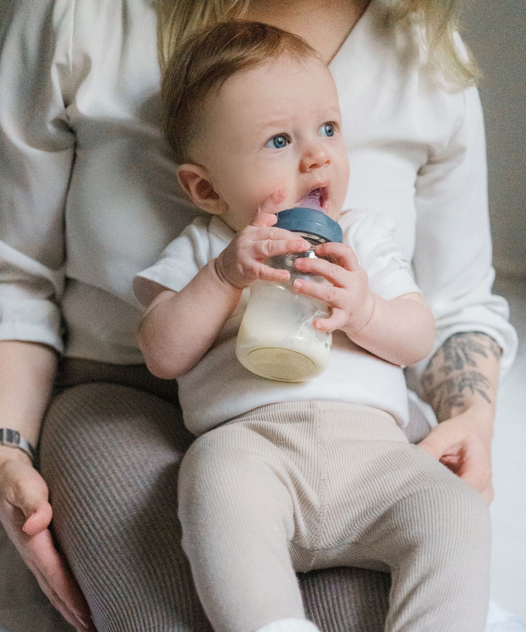 A baby drinking from the Lola & Lykke Natural Flow Baby Bottle with cap.