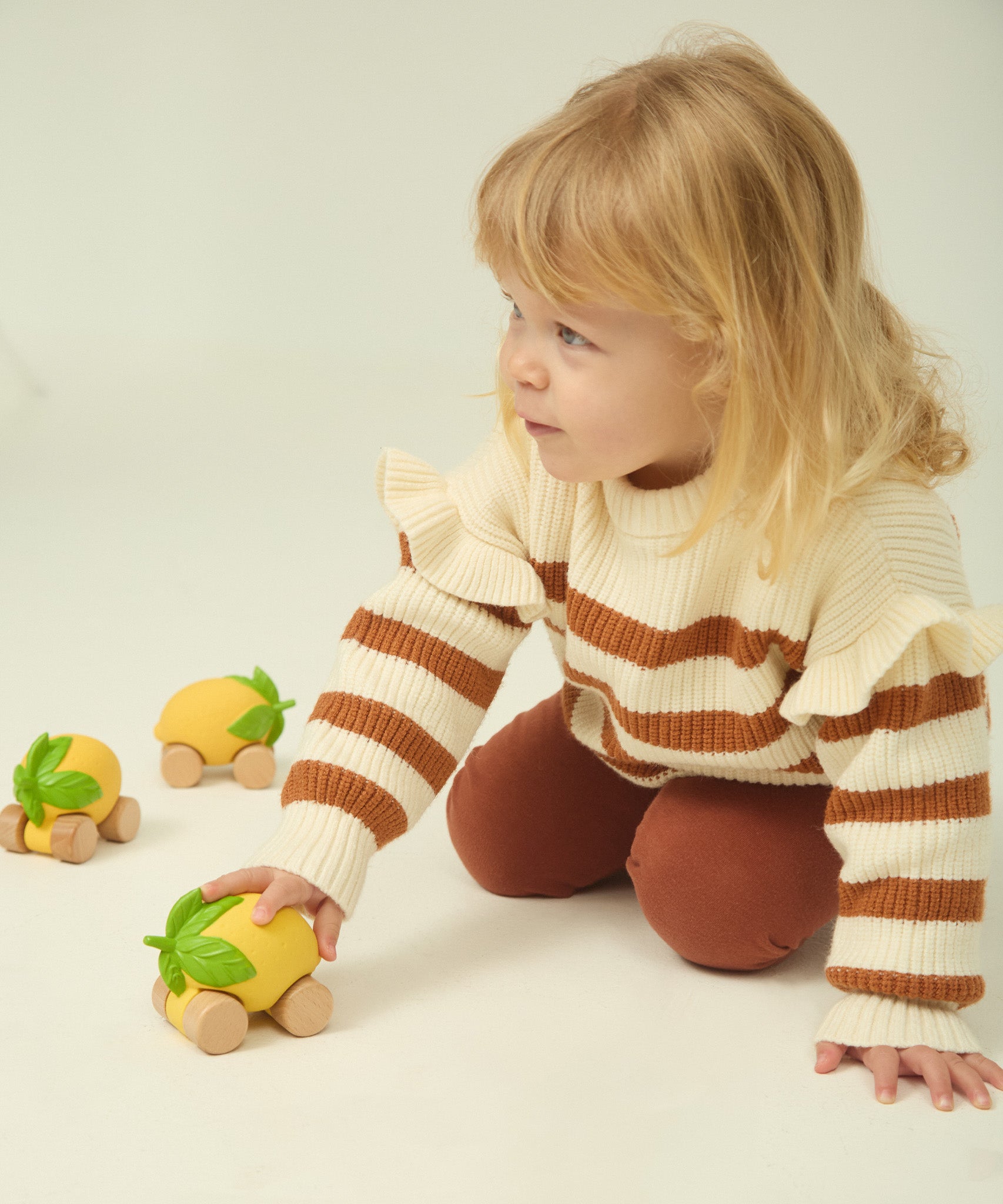 A child wheeling the Oli & Carol Lou the Lemon car across the ground