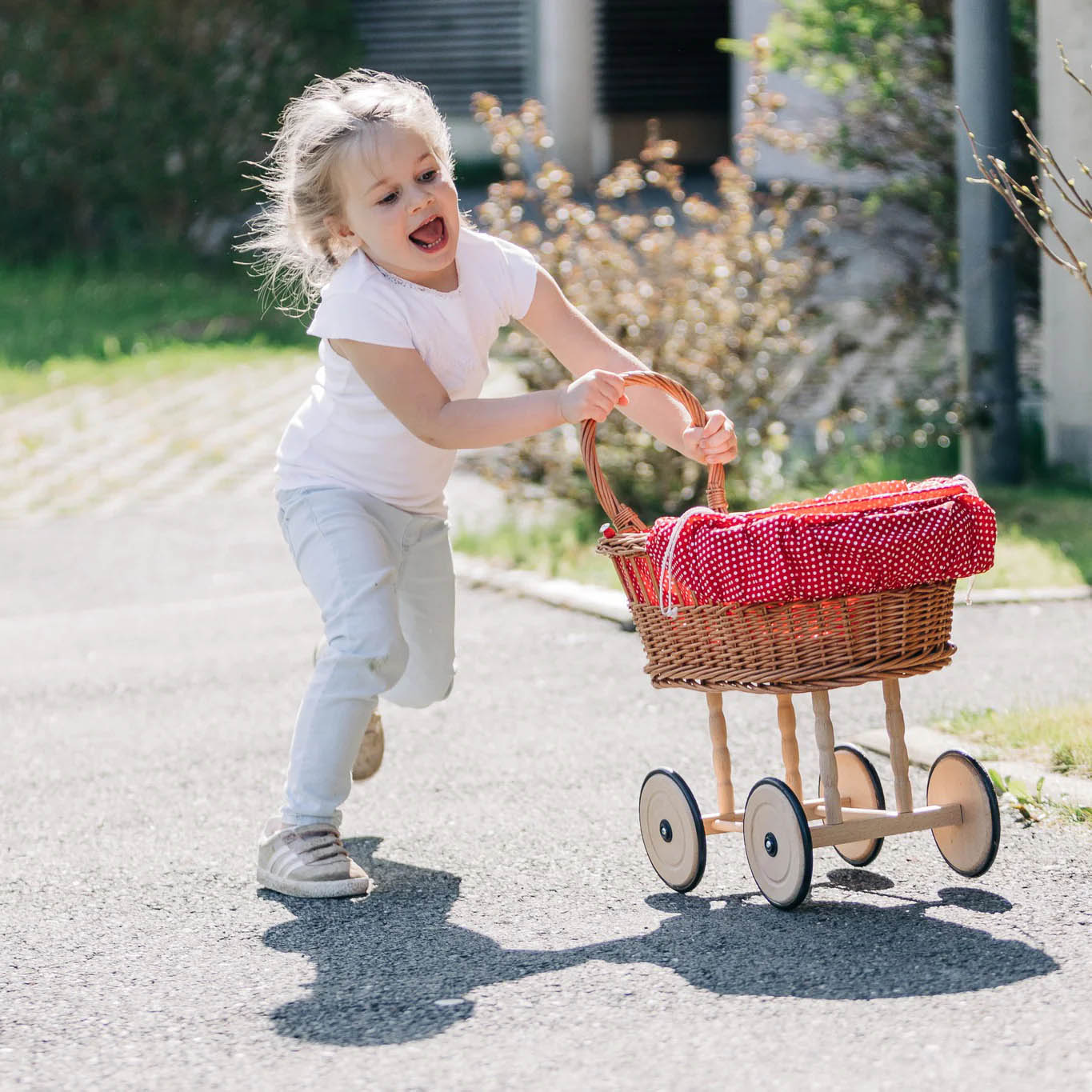 child playing with wicker basket style toy pram