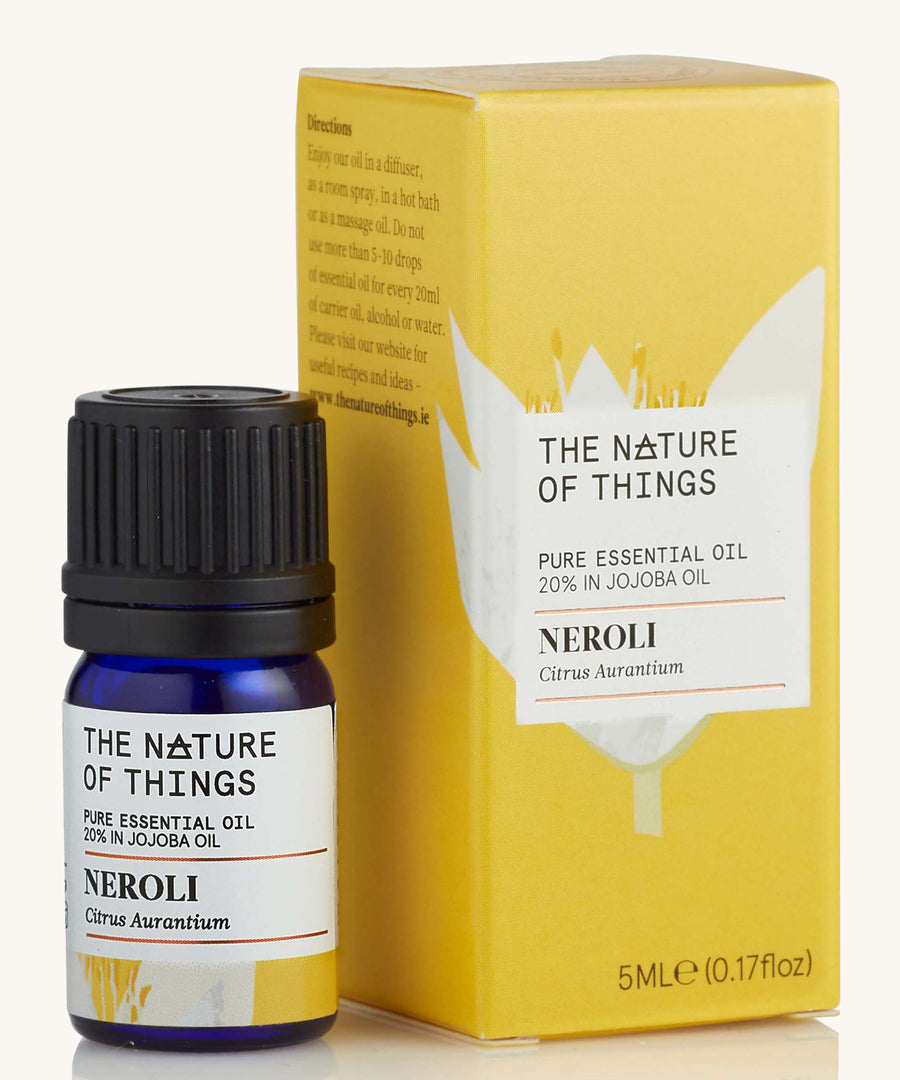 Neroli pure essential oil in a blue glass bottle in front of a decorative yellow cardboard box.