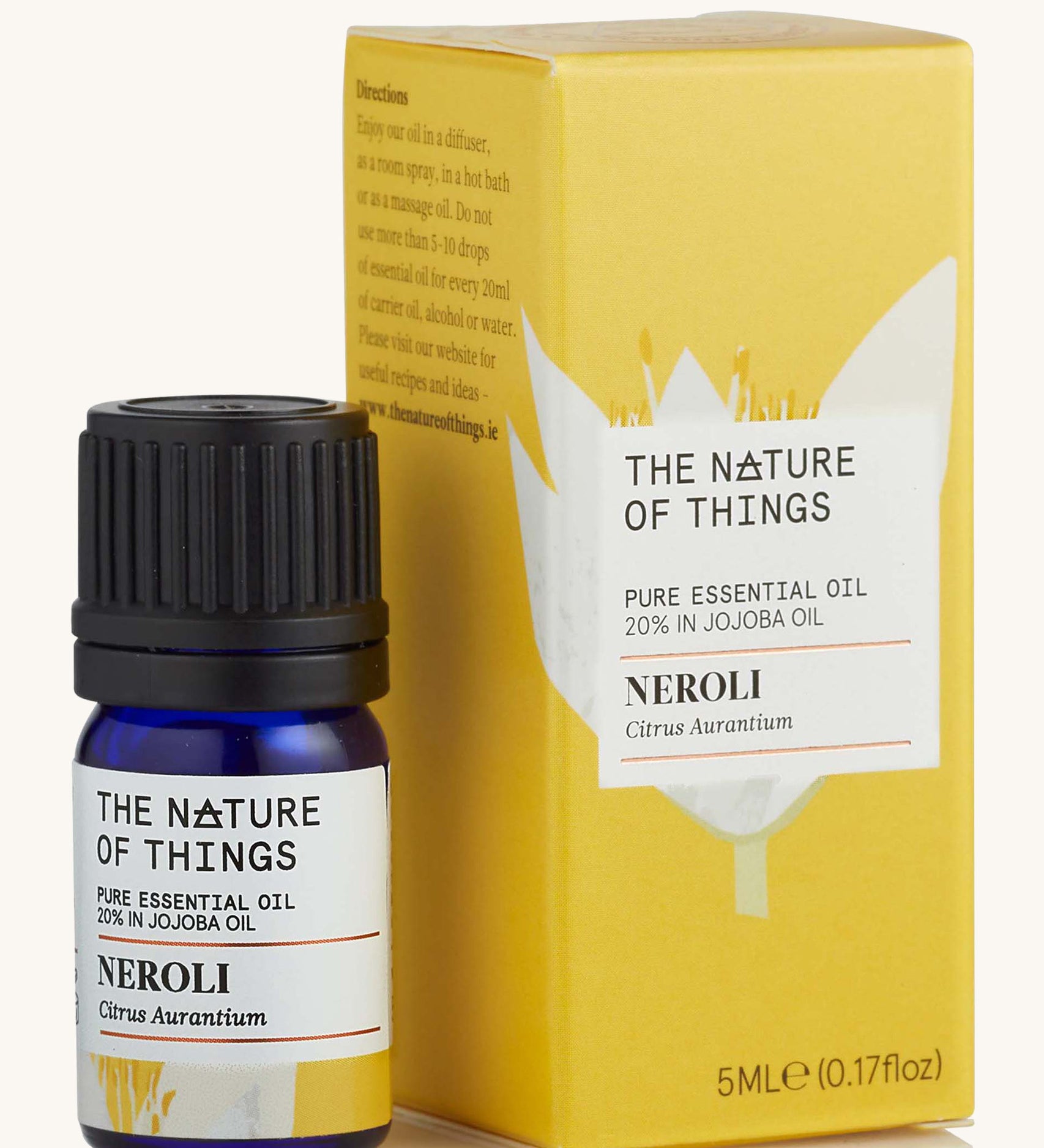 Neroli pure essential oil in a blue glass bottle in front of a decorative yellow cardboard box.