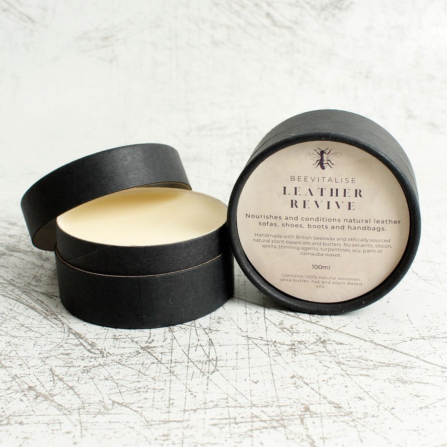 2 tubs of Oakdale Bees beevitalise leather revive balm on a white background next to a brown leather wallet