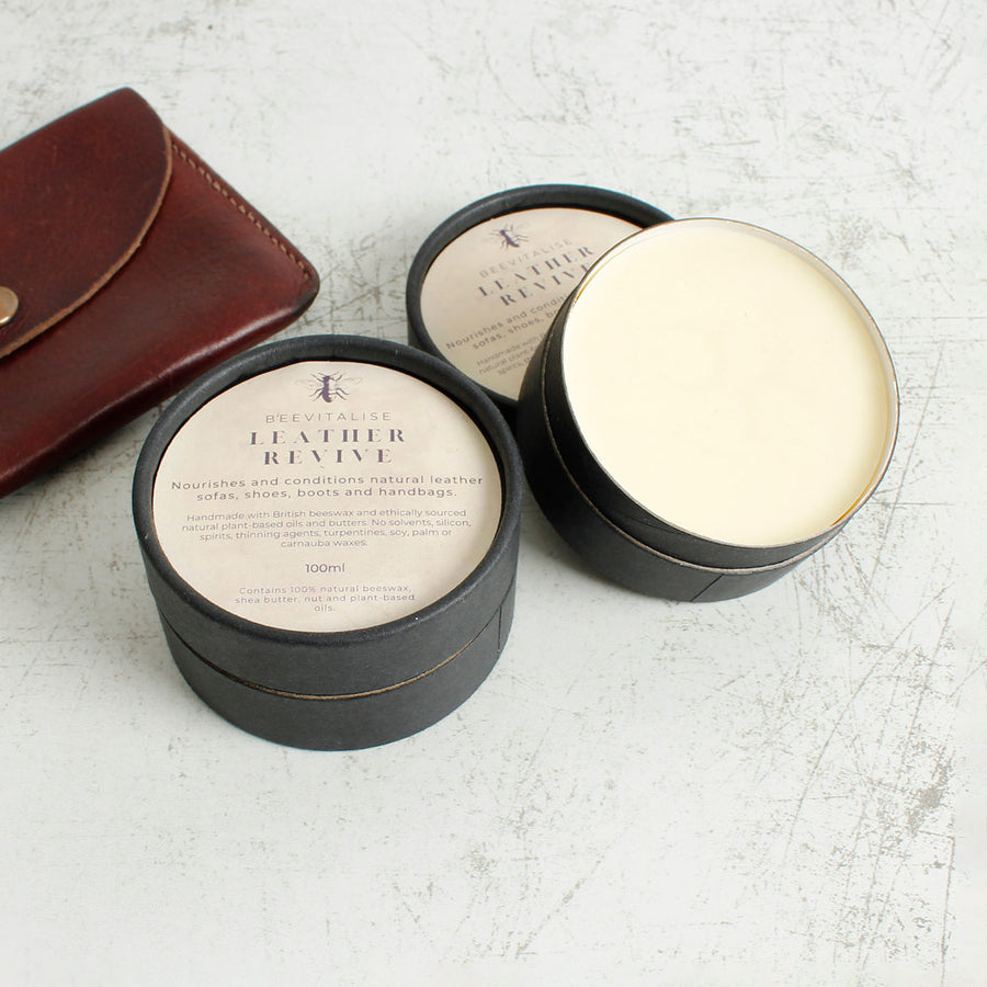 leather revive and board and bowl restore balm on a wooden floor next to a wooden chopping board and leather wallet