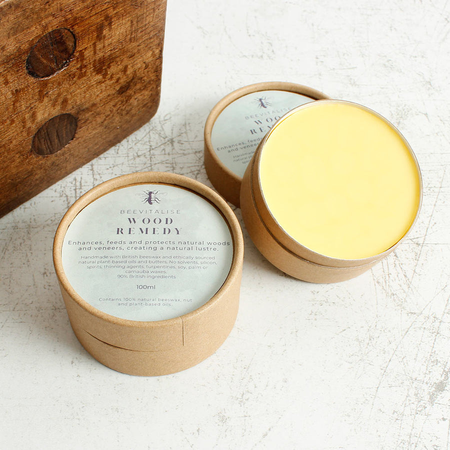 leather revive and board and bowl restore balm on a wooden floor next to a wooden chopping board and leather wallet