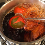 Eggs in a saucepan showing the OkoNorm egg dye kit in use. The egg has started dying in a pink toned colour. 