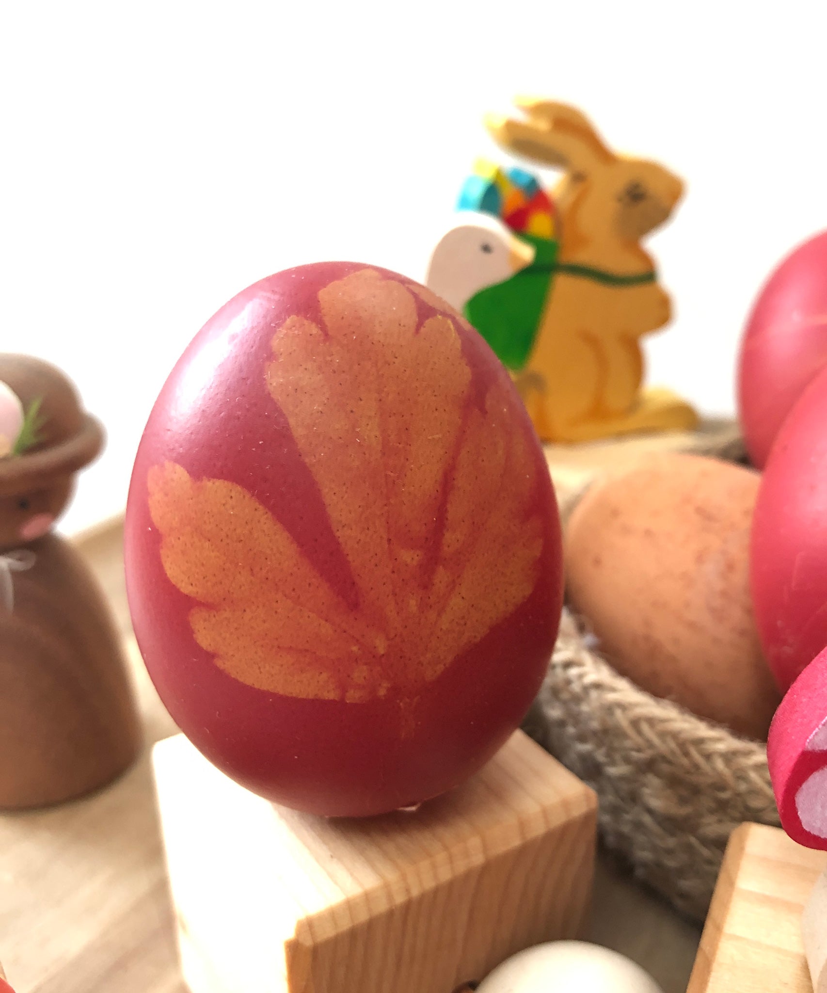 An egg dyed using the OkoNorm Egg dye kit in a pink colour with a leaf shape on the side.