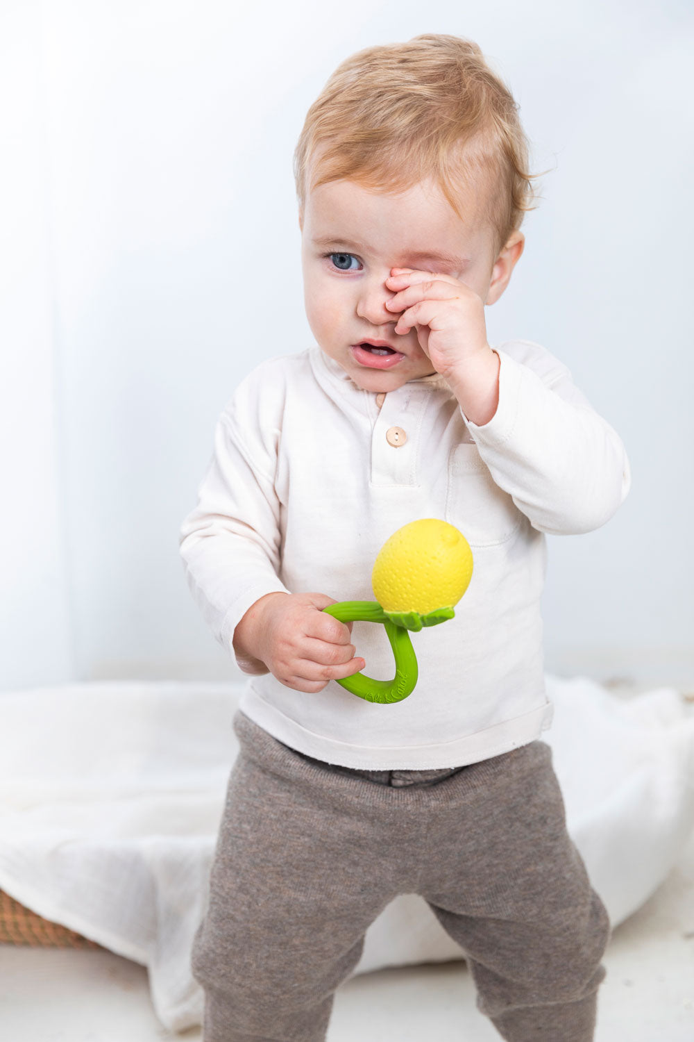 A child holding onto a Oli & Carol Lemon Rattle Teether