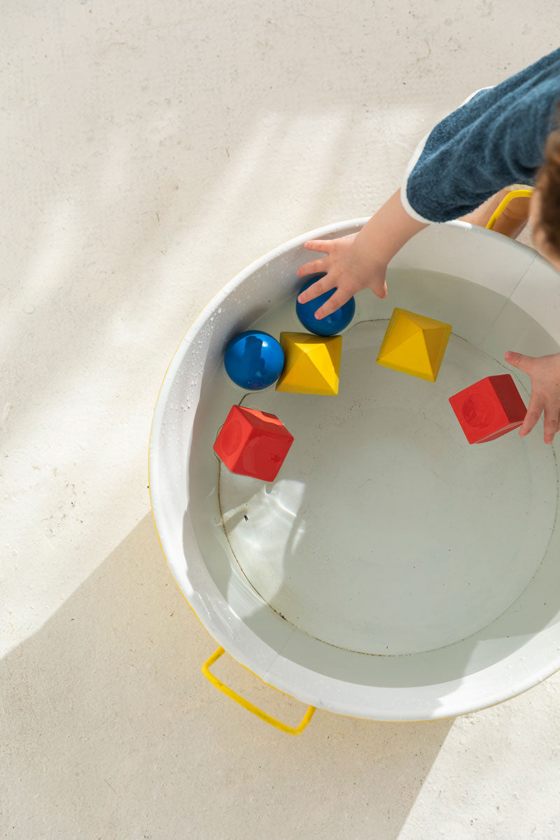 Oli & Carol X Bauhaus Movement Floating Geometric Blocks pictured floating in a metal tub full of water