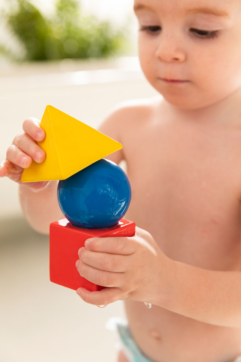 Child holding the Oli & Carol X Bauhaus Movement Floating Geometric Blocks which have water on them