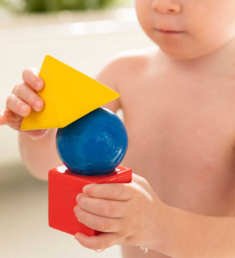 Child holding the Oli & Carol X Bauhaus Movement Floating Geometric Blocks which have water on them