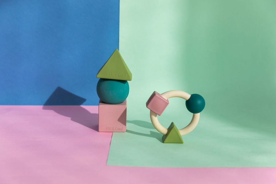 Oli & Carol X Bauhaus Movement Teething Ring and geometric floating stacking blocks in Pastel Colours pictured on a pastel pink