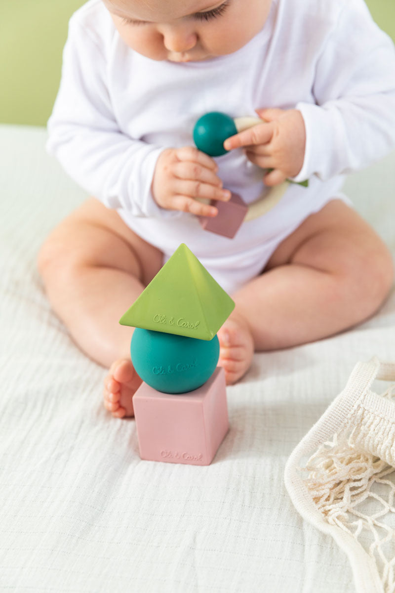 baby playing with teething ring with the Oli & Carol X Bauhaus Movement Floating Geometric Blocks in Pastel colours in front of them