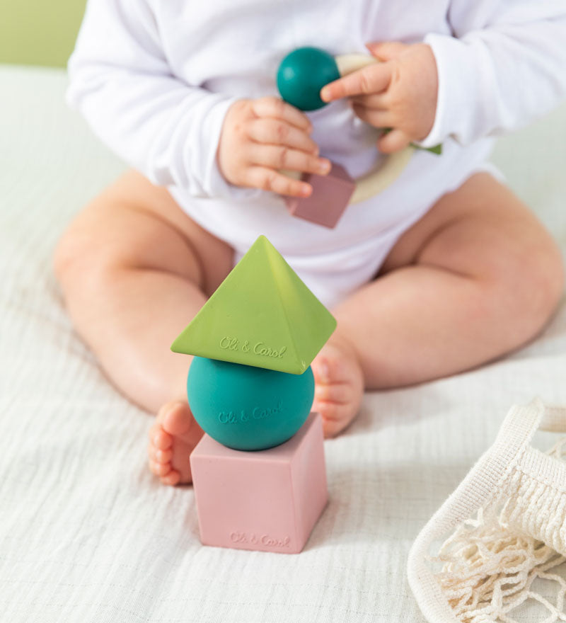 baby playing with teething ring with the Oli & Carol X Bauhaus Movement Floating Geometric Blocks in Pastel colours in front of them