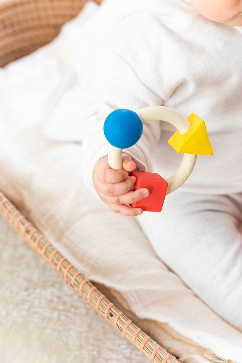 Baby clutching onto the Oli & Carol X Bauhaus Movement Teething Ring