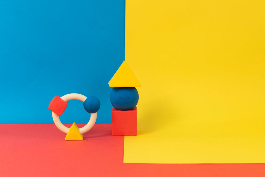 Oli & Carol X Bauhaus Movement Teething Ring and geometric shape figures pictured on a red