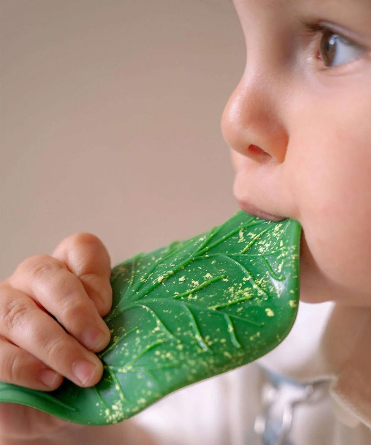 A baby chewing on the Oli & Carol green coloured Chlorophyll Leaf Baby Teether