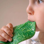 A baby chewing on the Oli & Carol green coloured Chlorophyll Leaf Baby Teether