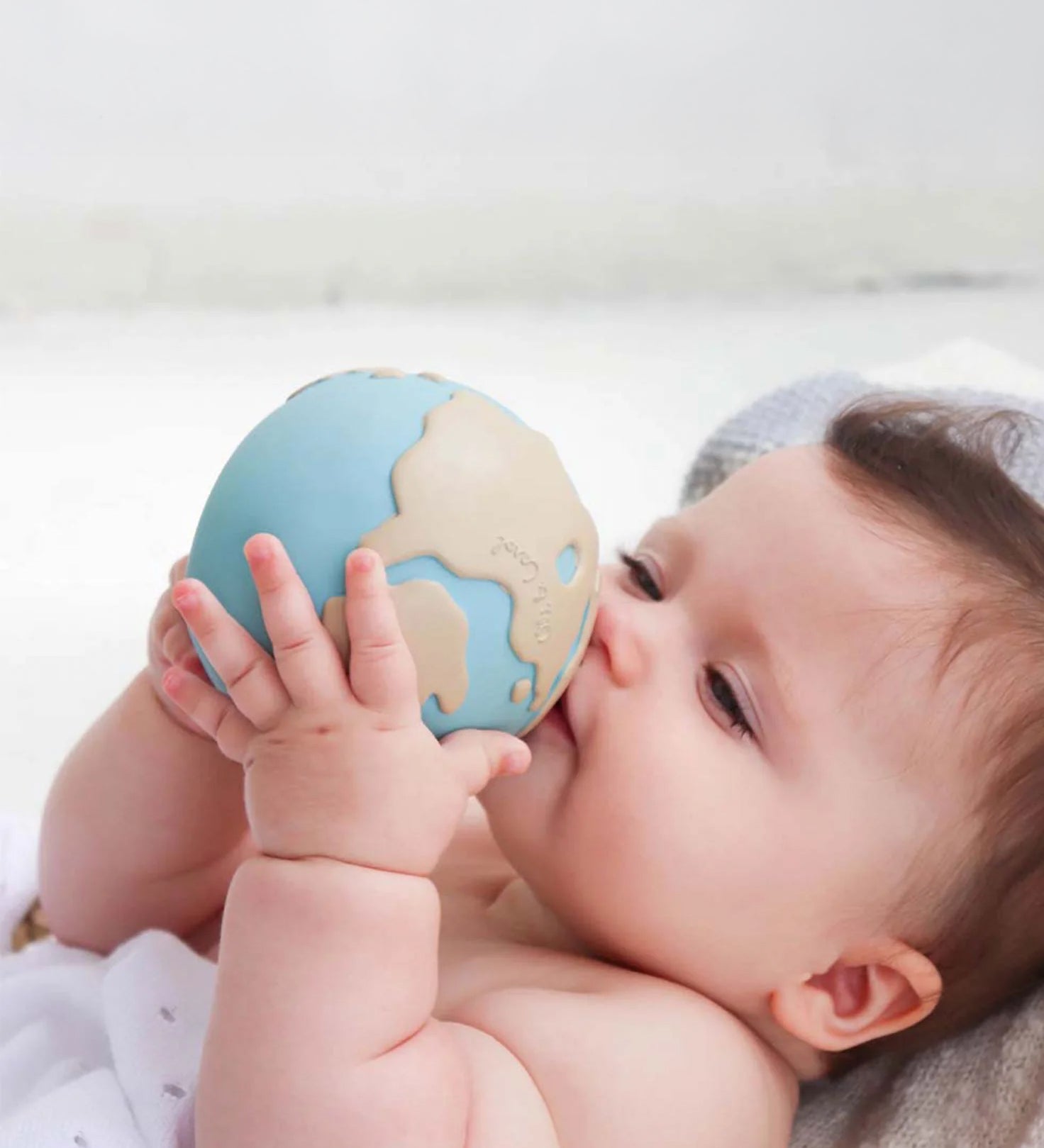 A baby holding the Oli &amp; Carol Earthy The World Ball in their hands.