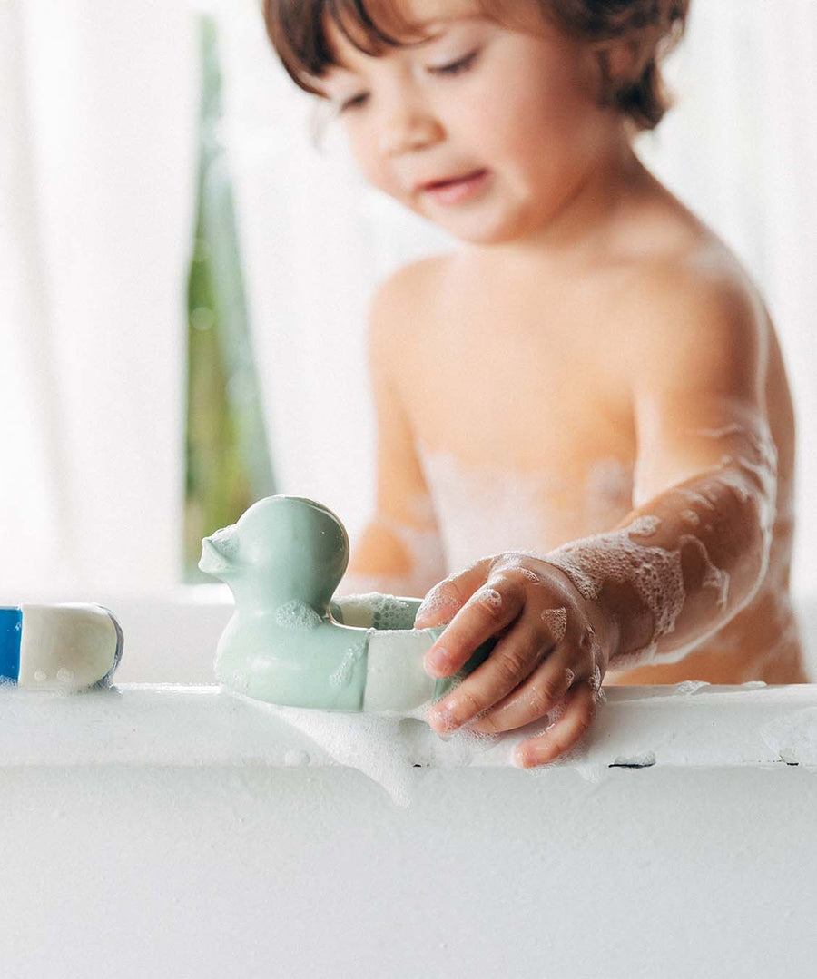 A child playing with the Oli & Carol Flo The Floatie Duck Mint in the bath. 