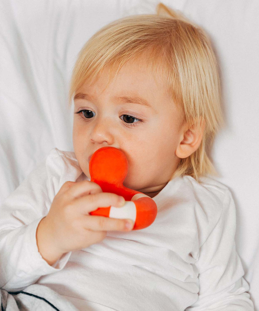 A child chewing on the Oli & Carol Flo The Floatie Duck Red.