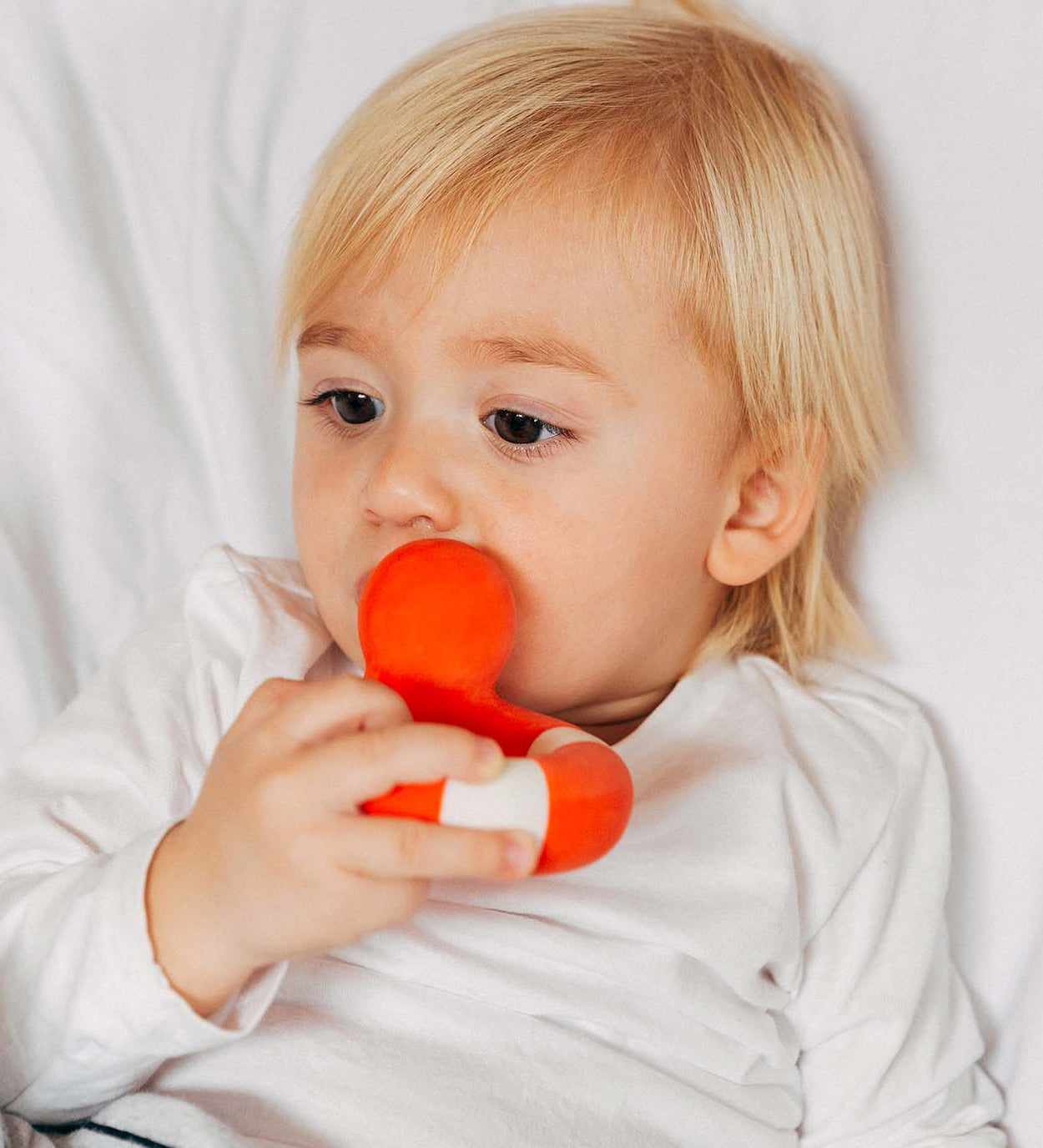 A child chewing on the Oli & Carol Flo The Floatie Duck Red.