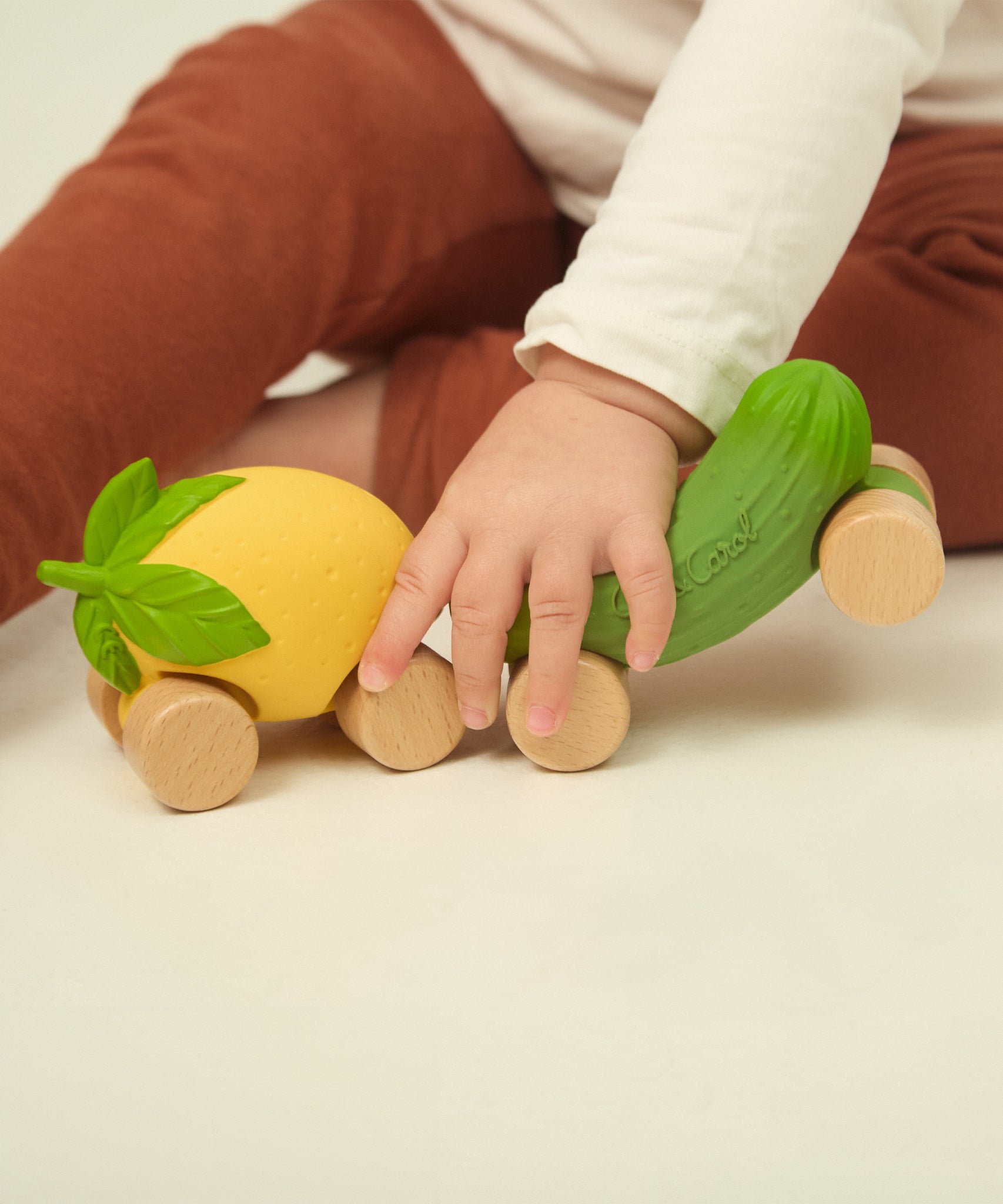 A child wheeling the Oli & Carol Lou the Lemon car across the ground