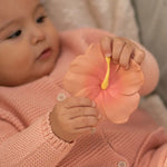 A baby holding onto the Oli & Carol Iris The Hibiscus Baby Teether