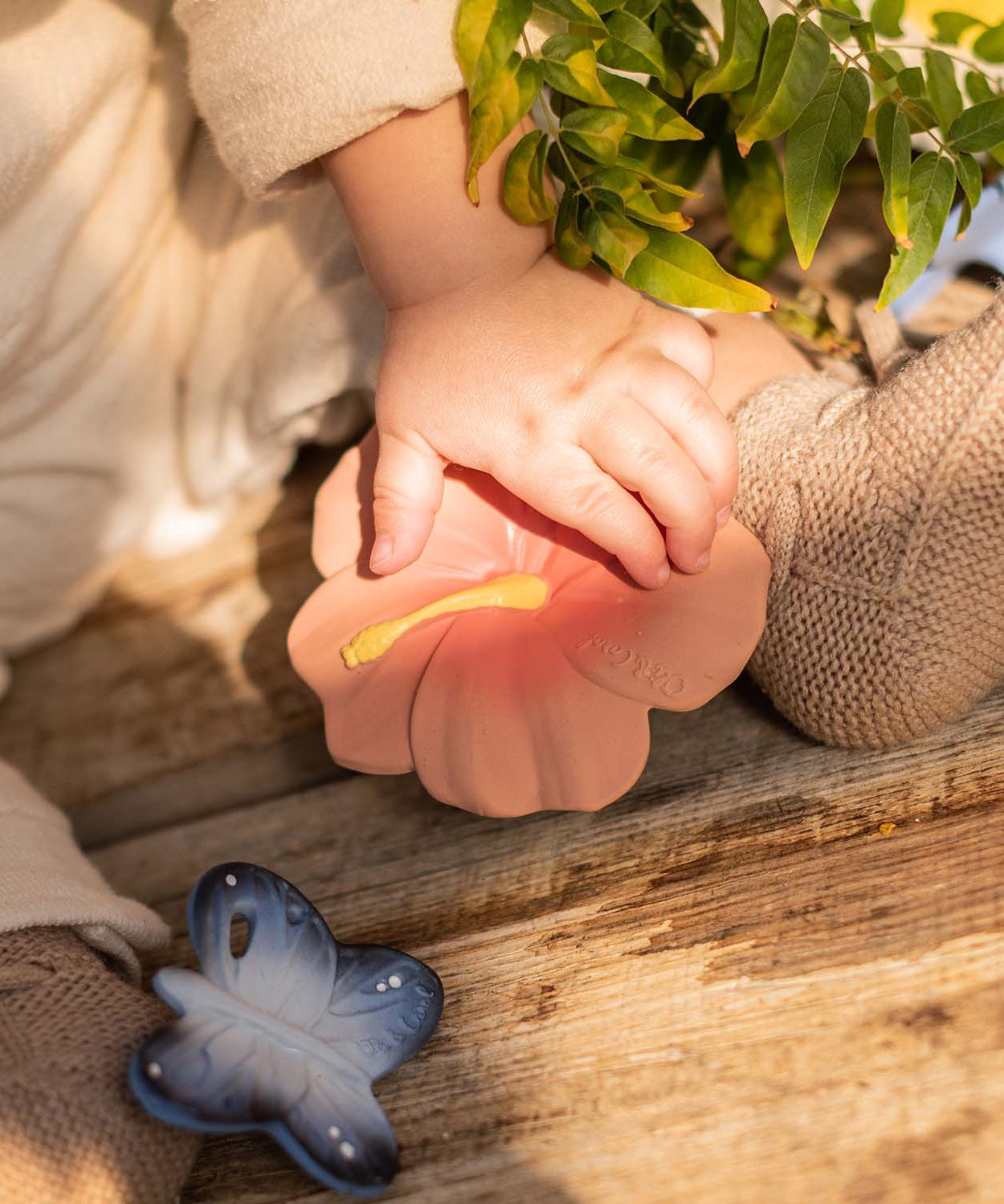 A close up of a baby's hand on the Oli & Carol Iris The Hibiscus Baby Teether