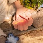 A close up of a baby's hand on the Oli & Carol Iris The Hibiscus Baby Teether