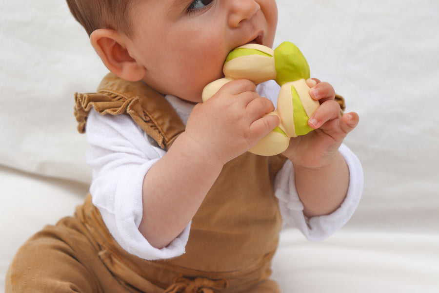 Close up of a toddler chewing on the oli and carol natural rubber pistachio soft food baby teether