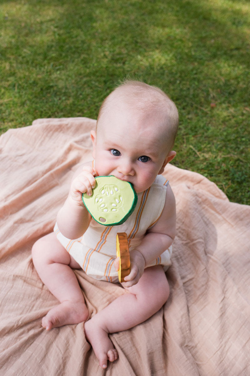 Baby clutching onto and chewing the Oli & Carol Pepino The Cucumber natural rubber toy