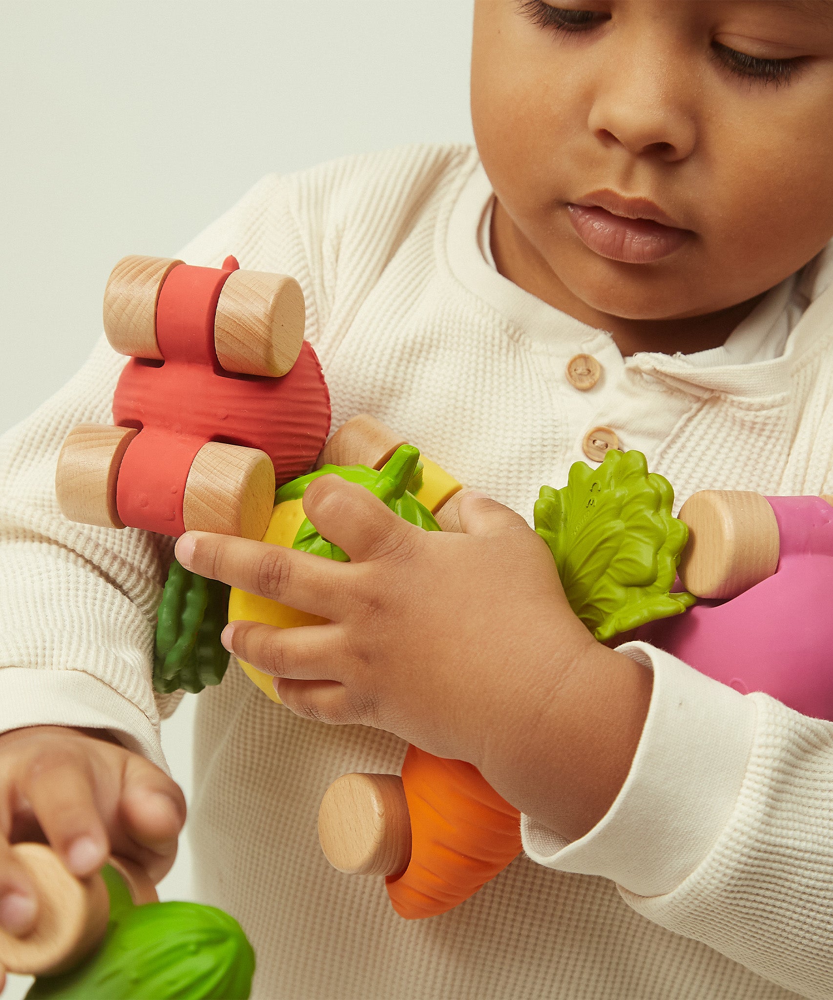 A child wheeling the Oli & Carol 100% Natural Rubber Emma the Eggplant Car in their hand