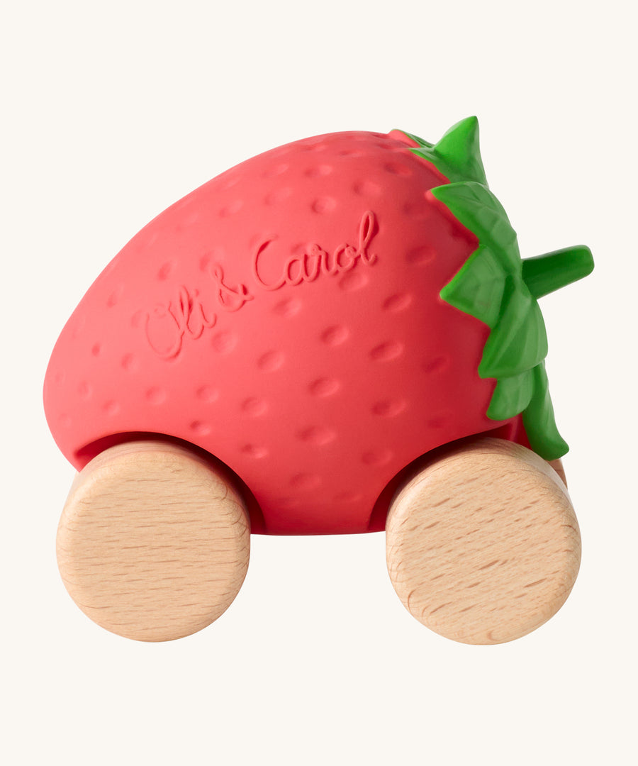 Oli & Carol Sweetie The Strawberry Baby Car. A fun red strawberry car with a green leafy top, and wooden wheels on a cream background