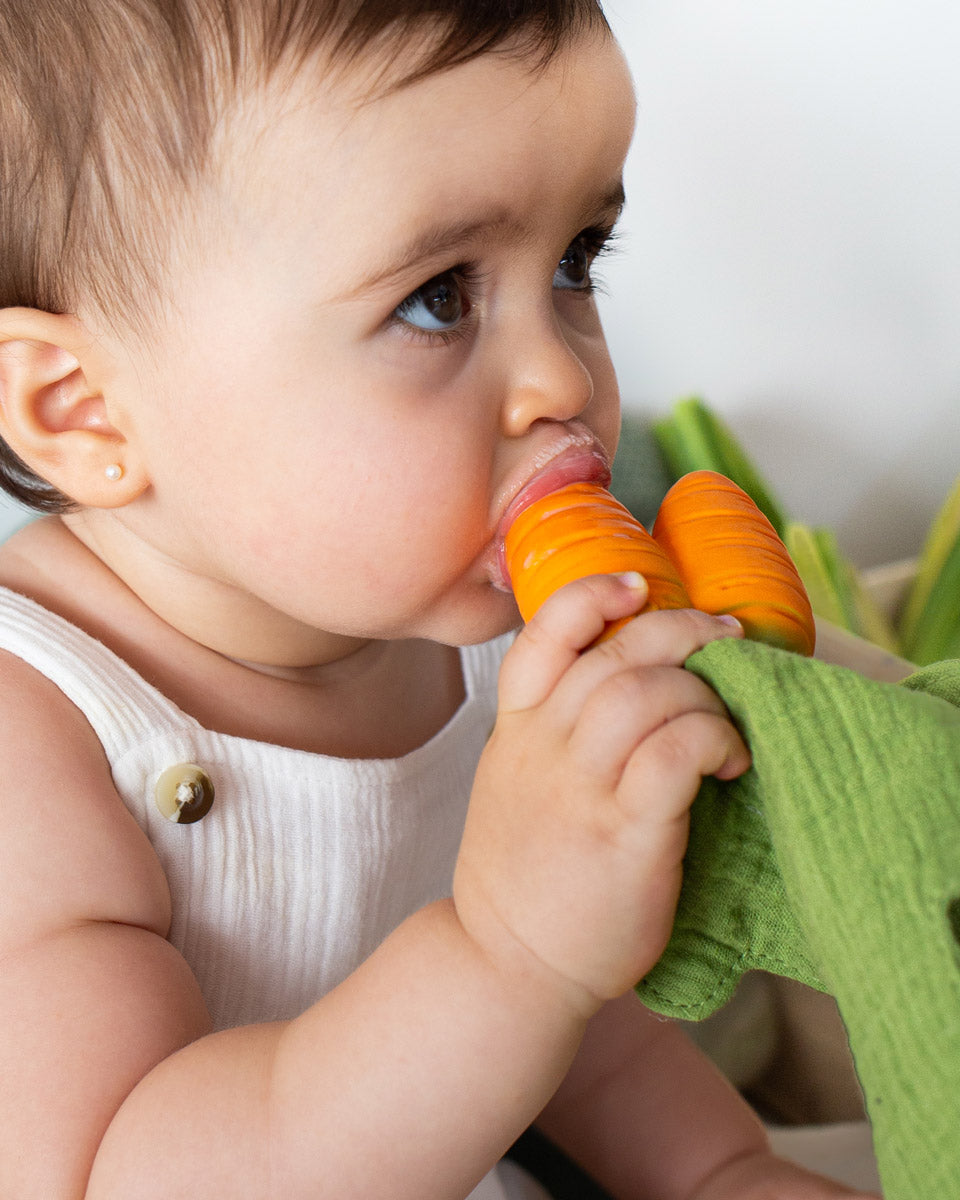 Close up of young child sucking on the Oli & Carol mini carrot baby teething toy